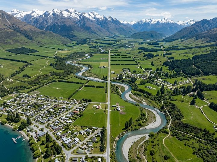 Two small towns in a wide green valley, joined by a straight country road beside a winding river